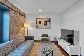 Una sala de estar moderna con un sofá, una silla, un televisor, una lámpara y una alfombra.