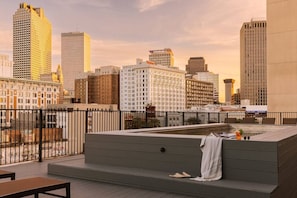 Una terraza en la azotea con vistas al horizonte de la ciudad, un área de estar y un jacuzzi.