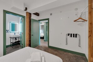 Habitació d'hotel amb llit, bany amb mirall i un penjador.