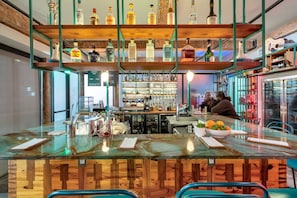 A bar area with a wooden counter, shelves with bottles, and a menu board.