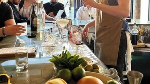 Eine Bar mit einem Barkeeper, der Getränke zubereitet, einer Speisekarte und einer Auswahl an Flaschen und Gläsern hinter der Theke.