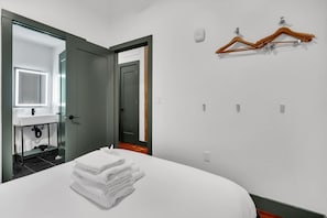 Habitació d'hotel amb llit, bany amb mirall, un lavabo i un assecaguts penjant a la paret.