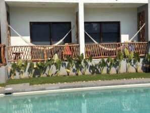 A poolside view of a hotel with a pool, a wooden fence, and some greenery. - Boutique Almendras (Acapulco)