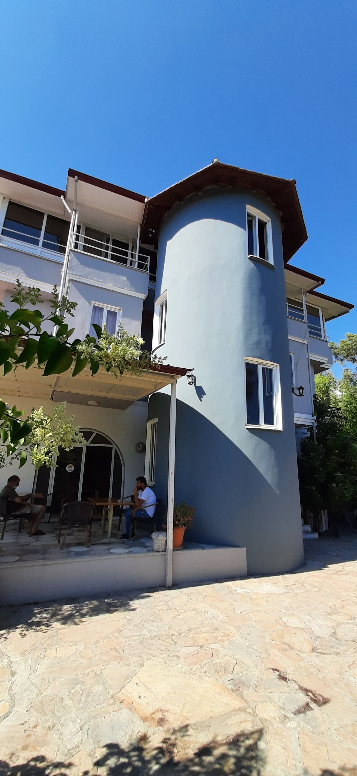 Ein zweistöckiges Gebäude mit einer gebogenen Ecke, Außenplätzen und einem Balkon.