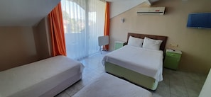 Una habitación de hotel con cama, mesita de noche, televisión y ventana con cortinas.