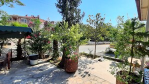 A patio area with potted plants, outdoor seating, and a street view. - TANGO PANSIYON (Koycegiz)