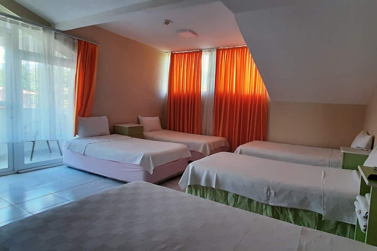 Habitación de hotel con dos camas, un escritorio verde y vistas al exterior.