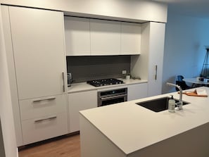 Eine moderne Küche mit weißen Schränken, einem Gasherd, einem Backofen und einem Spülbecken.