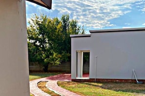 A modern building with a flat roof, a door, and a brick pathway leading to it.