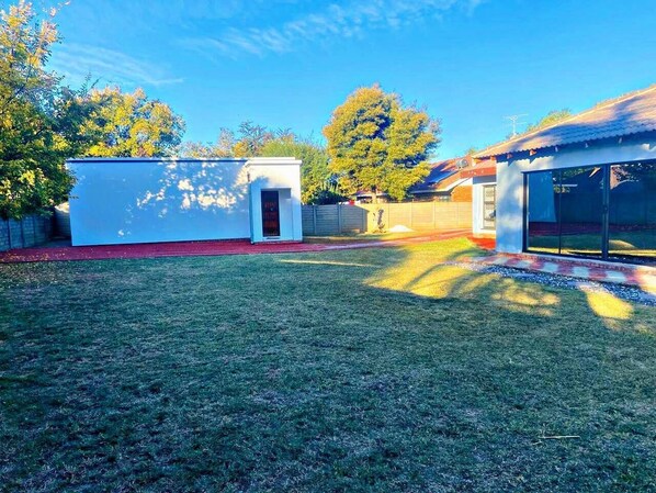 A backyard with a small shed, a covered area, and a tree.