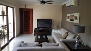 Un salon moderne avec un canapé, une table basse, un téléviseur et un ventilateur de plafond.