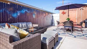 Eine Terrasse mit Korbmöbeln, einer Feuerstelle und einer Zierwand.