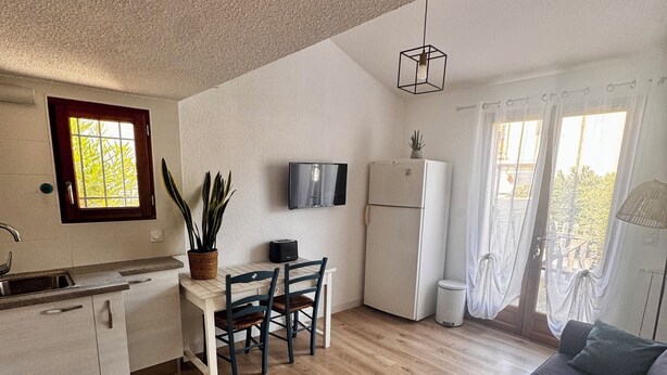 Una cocina compacta con comedor, sofá y televisor.