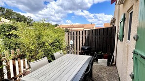 Un patio con una mesa, sillas, una cerca de madera y un edificio con una puerta verde.