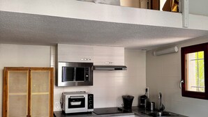 Cocina compacta con lavadora, microondas y un lavamanos pequeño.