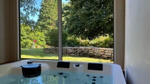 Ein Whirlpool mit Steinwand und umliegender Bepflanzung.