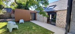 Ein Garten mit einem Steinhaus, einem Holzzaun und zwei weißen Stühlen.