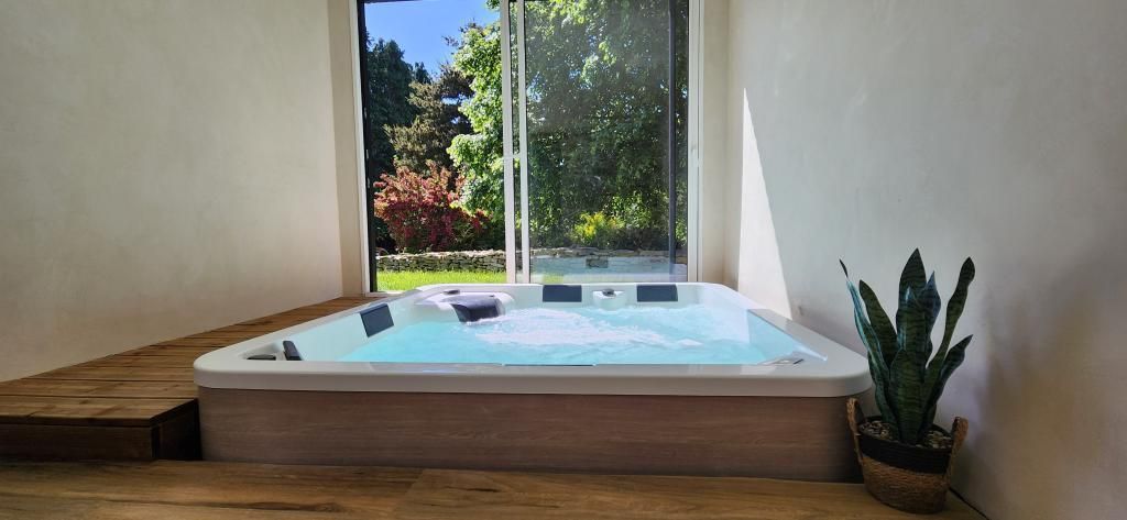 A hot tub in a corner with a view of greenery outside.