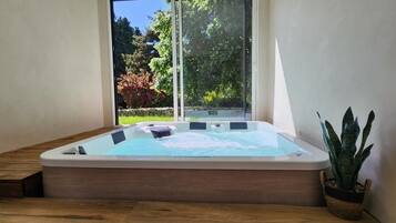 A hot tub in a corner with a view of greenery outside.