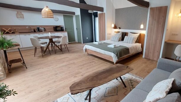 A modern interior with a bed, sofa, dining table, and kitchen area. - Le Clos de Squividan - L'Évasion (Ergué-Gabéric)