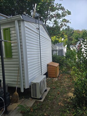 Ein Wohnmobil mit Satellitenschüssel, Klimaanlage und einem an der Wand angelehnten Besen.