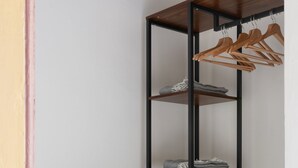 Um guarda-roupa com várias prateleiras, um cabideiro e uma pequena cesta.