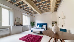 Quarto com cama, mesa de cabeceira e uma janela grande.