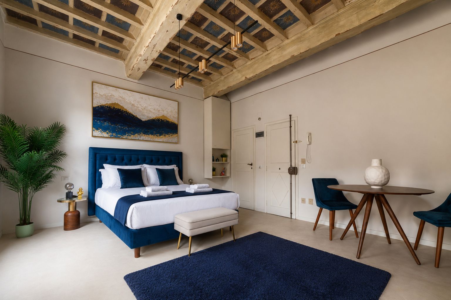 Ein Schlafzimmer mit einem großen Bett, einem Nachttisch, einem Stuhl, einem kleinen Tisch und einer Zimmerpflanze.