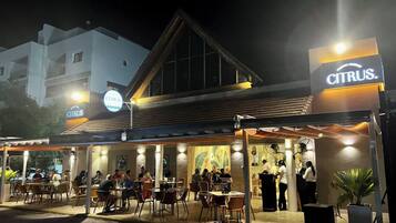 An outdoor seating area of a restaurant with tables and chairs, a covered section, and a sign for 'CITRUS.'