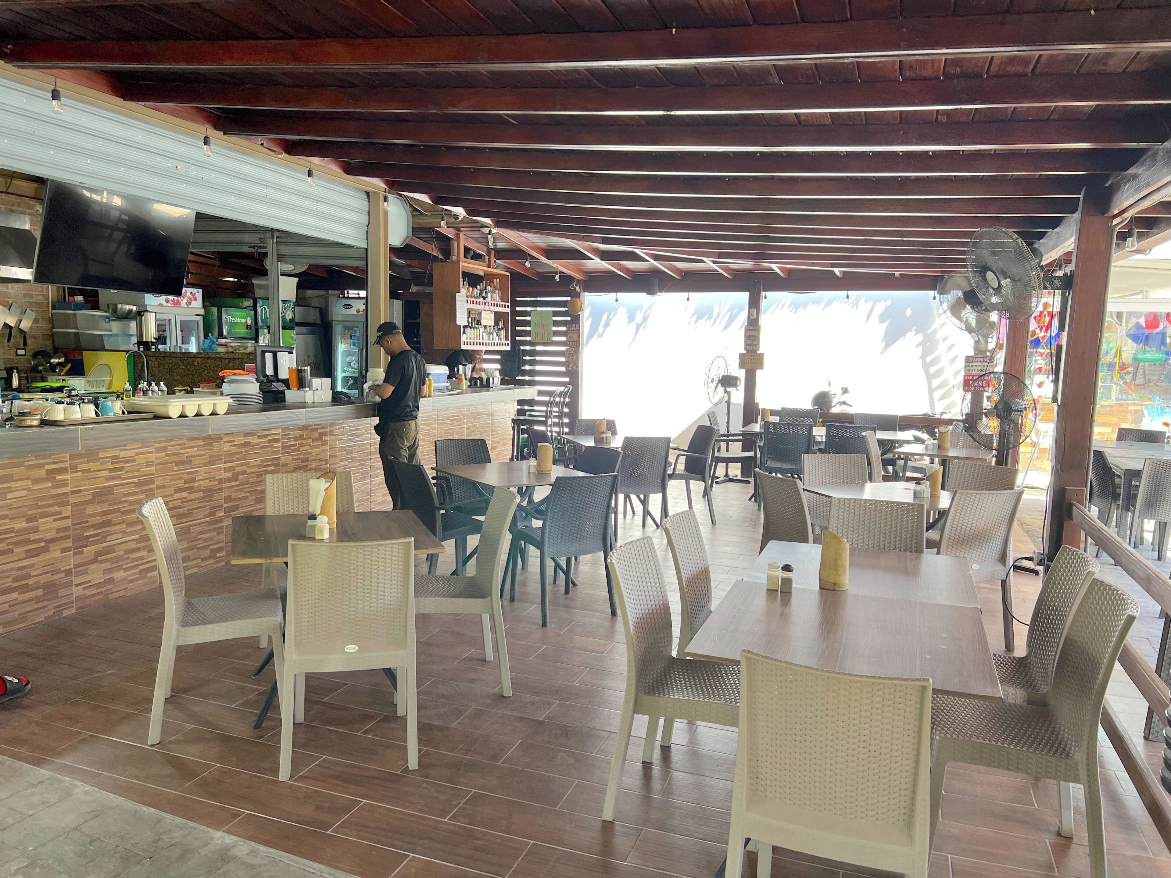 A restaurant with outdoor seating, a counter, and a view of the sea.