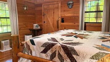 A wooden cabin room with a bed, a window, and a door.