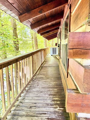 Eine Holzterrasse mit Geländer, die zu einem Gebäude mit großen Fenstern führt.