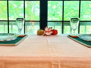 Une table dressée avec un saladier en verre transparent, un verre et une citrouille décorative portant l’inscription « Merci ».