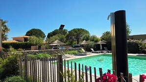 Una piscina con sillas de descanso, una valla de madera y sombrillas.