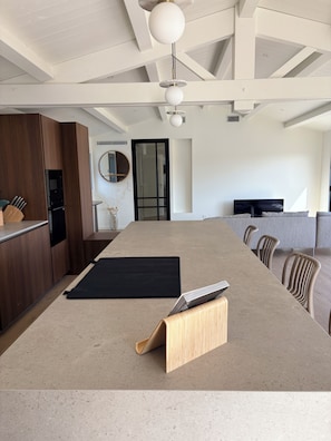 A modern kitchen with a large island, wooden cabinets, and a black mat on the countertop. - Doudou House. Exceptional family home with swimming pool in Oléron (Saint-Denis-d'Oléron)