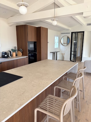 A modern kitchen with a central island, wooden cabinets, and a dining area with chairs. - Doudou House. Exceptional family home with swimming pool in Oléron (Saint-Denis-d'Oléron)