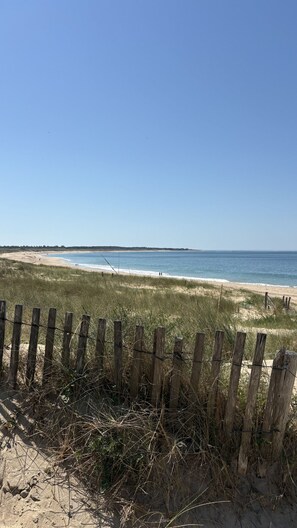 A beach with a wooden fence in the foreground, sandy beach, and a clear blue sky. - Doudou House. Exceptional family home with swimming pool in Oléron (Saint-Denis-d'Oléron)