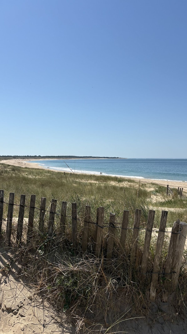 A beach with a wooden fence in the foreground, sandy beach, and a clear blue sky. - Doudou House. Exceptional family home with swimming pool in Oléron (Saint-Denis-d'Oléron)