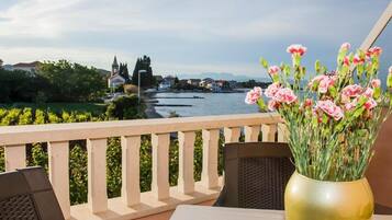 Een balkon met uitzicht op een rivier, een bloevas en een tafel met stoelen.