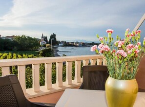 Ein Balkon mit Blick auf einen Fluss, eine Blumenvase und ein Tisch mit Stühlen.