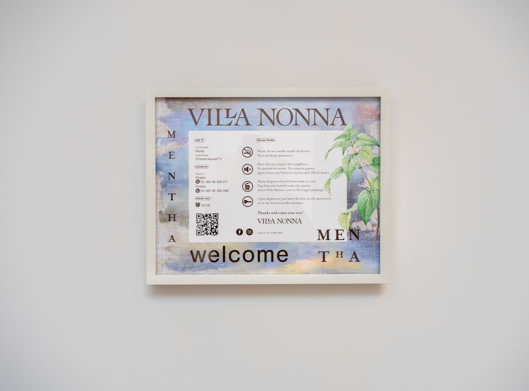 A framed welcome sign for Vila Nonna with contact details, WiFi password, and house rules.
