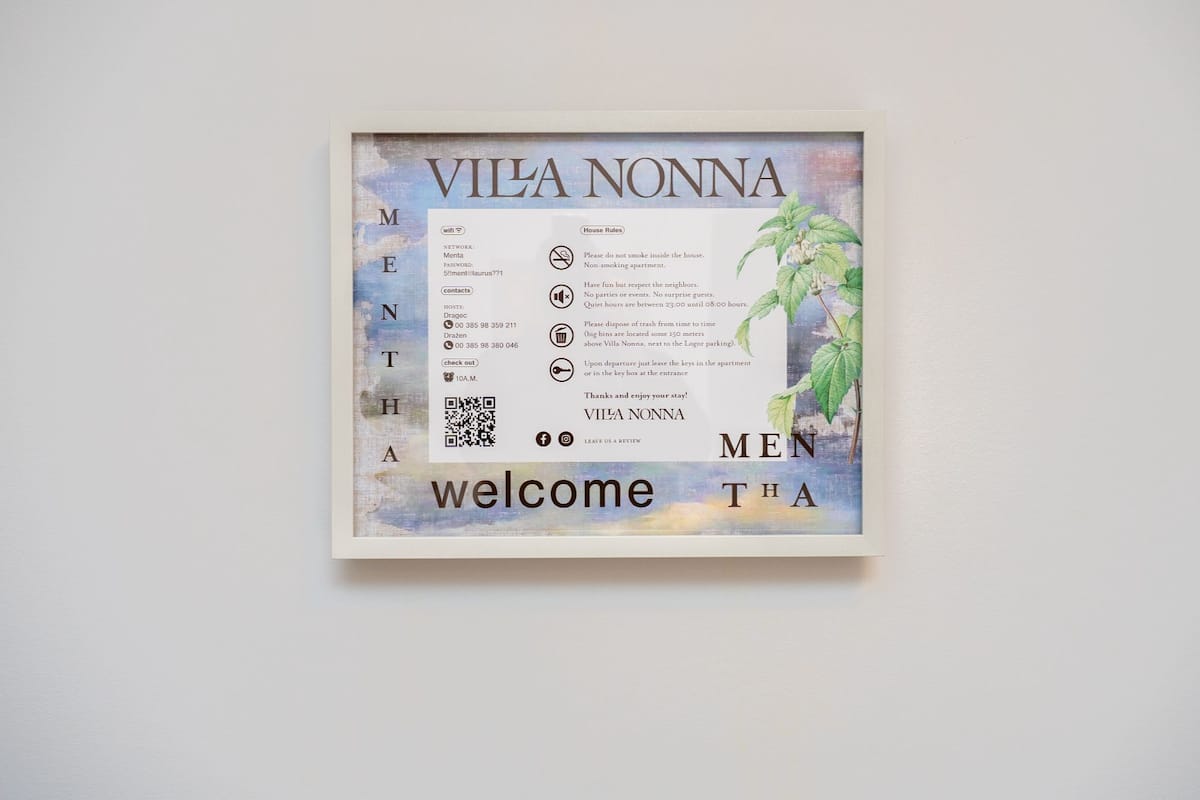 A framed welcome sign for Vila Nonna with contact details, WiFi password, and house rules.