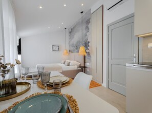 A modern hotel room with a dining area, a bed, and a kitchenette. - Apartments Nonna (Komiza)