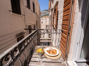 A narrow alleyway with a wooden bench, a wicker basket, and a plate of pastries. - Apartments Nonna (Komiza)