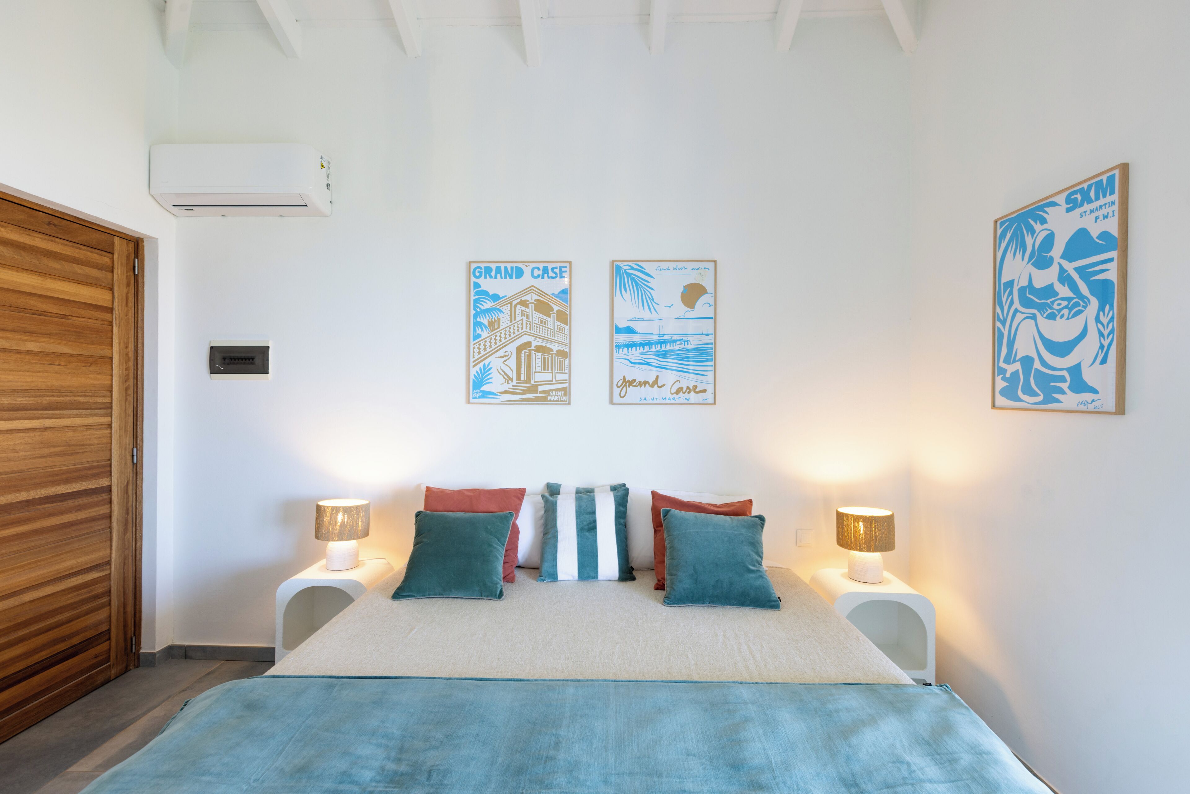 A bedroom with a bed, two nightstands, a wooden door, and wall art.