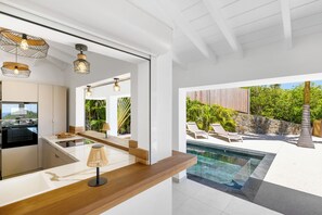A modern kitchen with a wooden countertop, built-in oven, and a view of a swimming pool and outdoor area. - Splendid sea view, close to beaches. (SAINT-MARTIN)