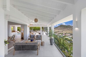 A spacious balcony with a view of a mountainous landscape, furnished with a sofa, chairs, and a table. - Splendid sea view, close to beaches. (SAINT-MARTIN)