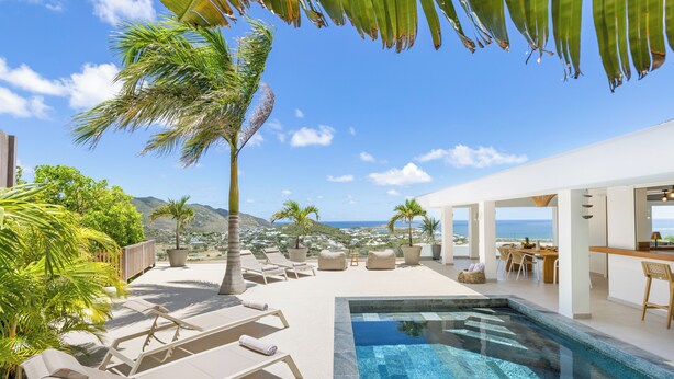 Área da piscina com espreguiçadeiras, uma piscina pequena e vista para o oceano.