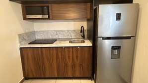 Eine kleine Küche mit Mikrowelle, Edelstahlkühlschrank und Spüle.