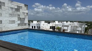 Ein Pool auf dem Dach mit Blick auf Gebäude und einen klaren Himmel.